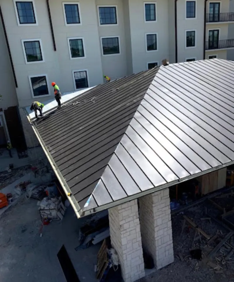 Crew installing standing seam metal roof panels on a commercial project in Claiborne